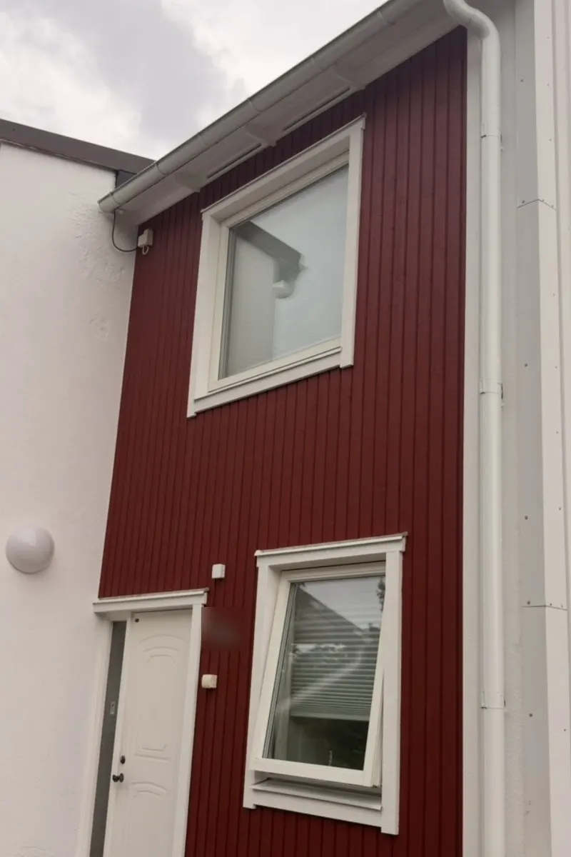 Samma radhus med ny röd panel efter fasadbytet