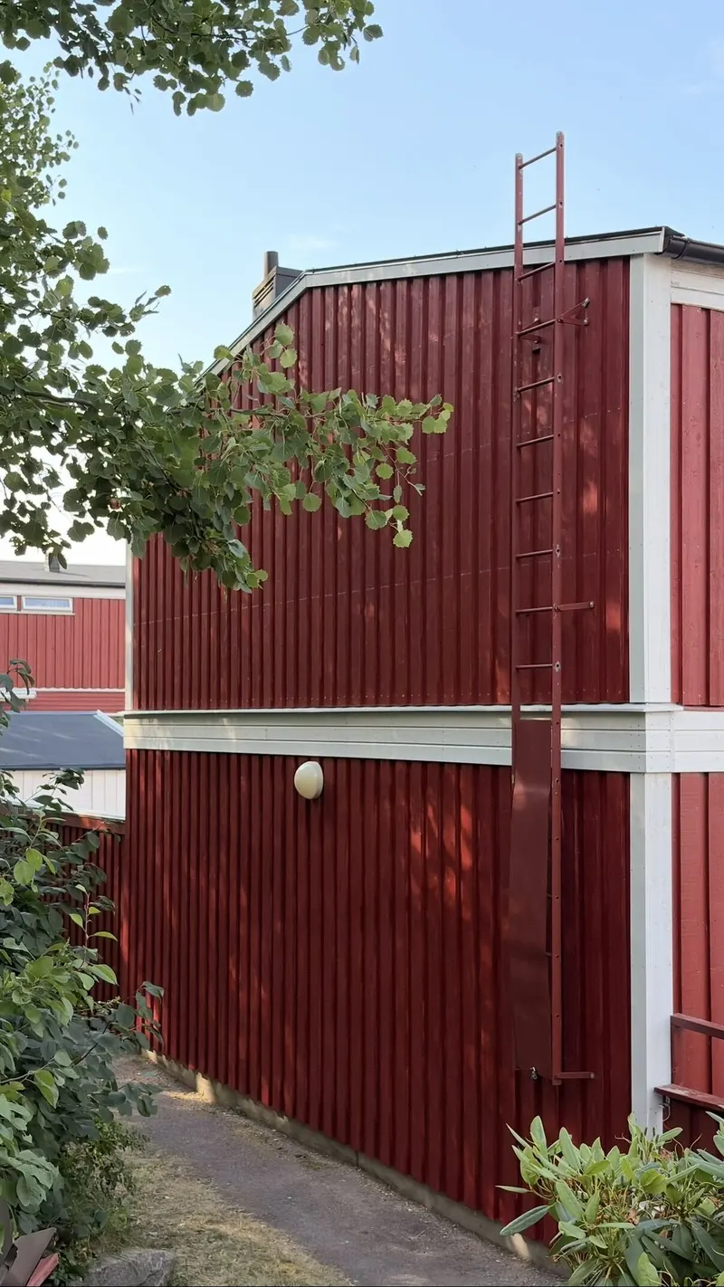 Röd fasad på gavel med stege upp till taket